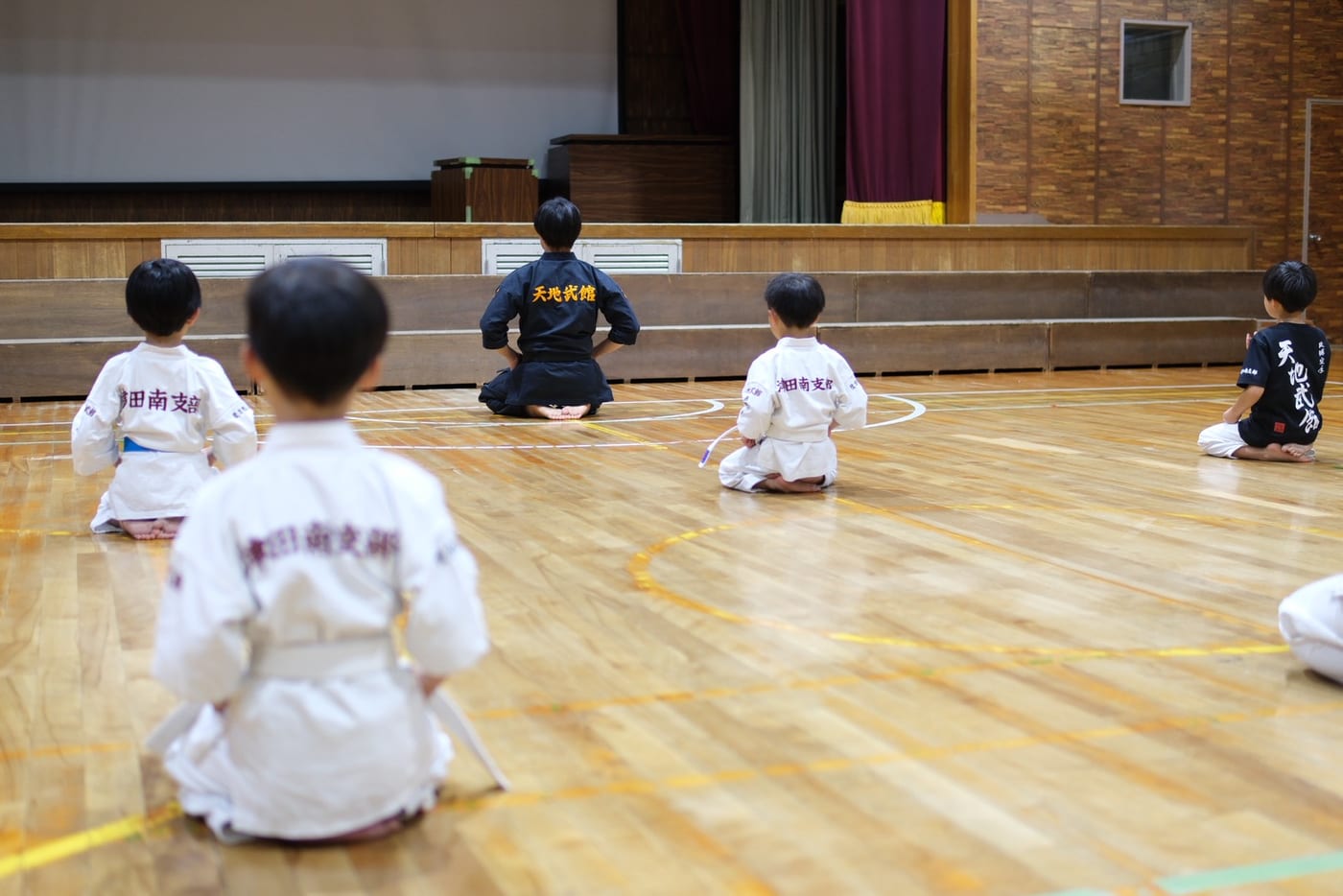 枚方市立津田南小学校の体育館で正座し、稽古に臨む天地武館の子どもたち